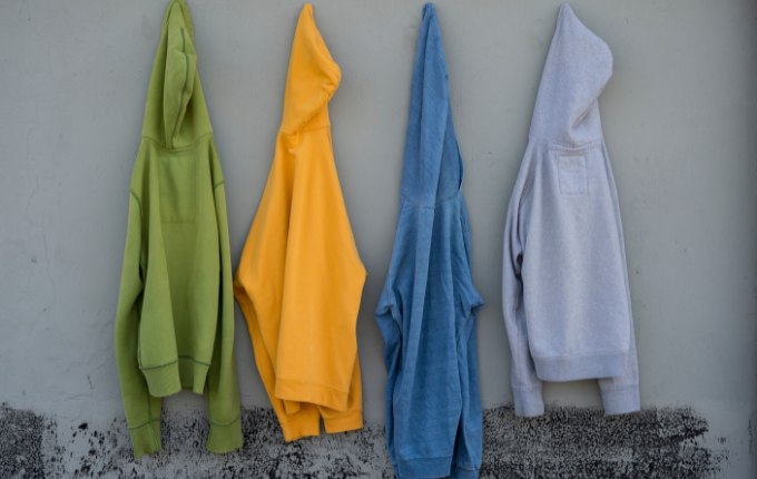 Green, yellow, blue and gray hooded sweatshirts hanging on a wal