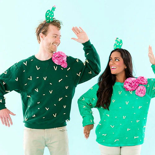 A man and woman wearing green crewneck sweatshirts that have been decorated to create cactus costumes for Halloween.