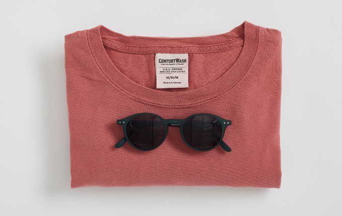 ComfortWash by Hanes garment-dyed shirt folded with a pair of black sunglasses on sitting on top. 