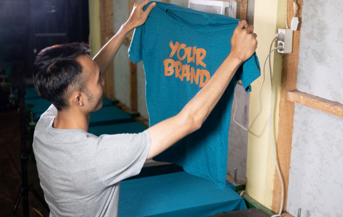 Man showing off a simple screen printed design on a blue t-shirt. 