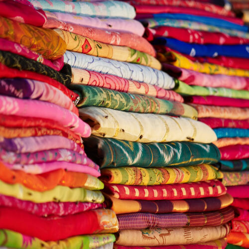Very colorful shirts folded and stacked on top of each other. 