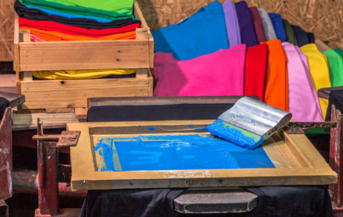 Colorful t-shirts in wood crates, awaiting to be screen printed.