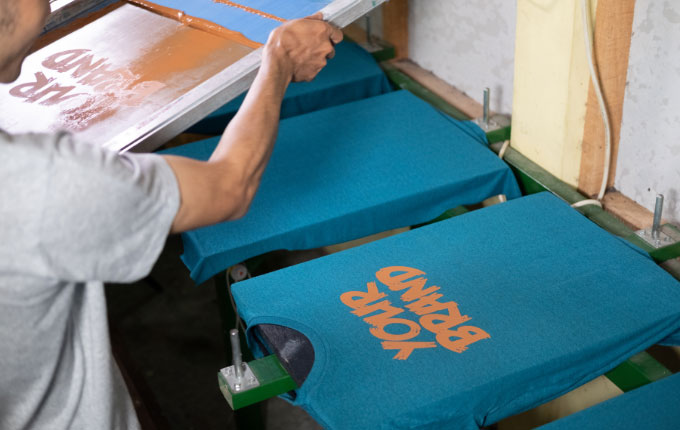 Man removing a screen to reveal his screen printed design.