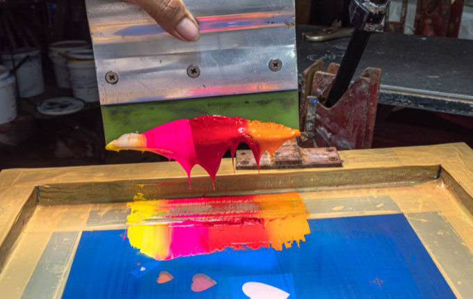 Colorful ink ready to be moved over a screen with a squeegee for screen printing.
