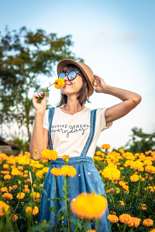 Girl smelling a yellow flower while standing in a field of flowers enjoying the Spring time air.
