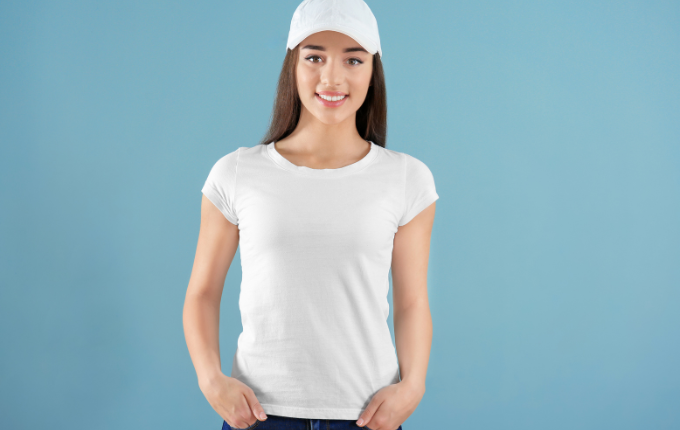 Woman wearing a white t-shirt with cap sleeves and white baseball cap.