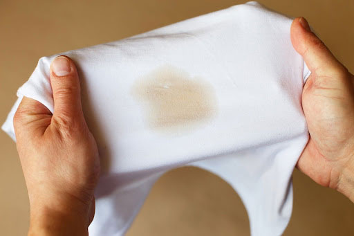Person holding a white piece of clothing stained with coffee. 