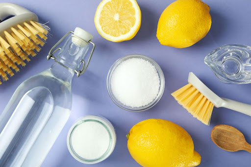 Items used to remove stains, including lemons, scrub brushes, vinegar, bleach and OxiClean detergent. 