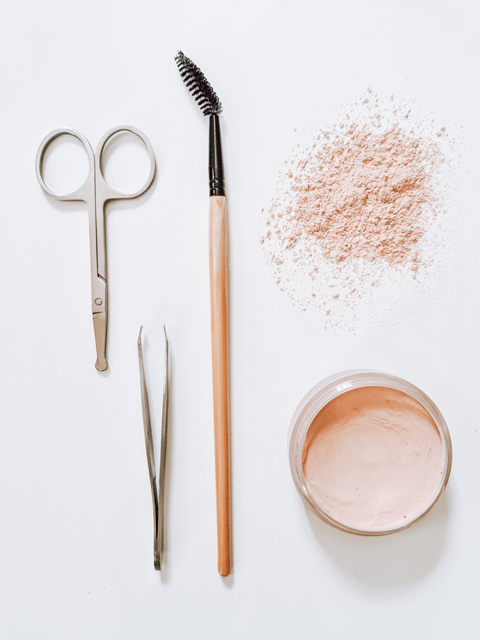 Makeup tools, including: cosmetic scissors, tweezers, an eyelash wand and loose powder.