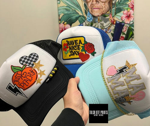 Three trucker hats decorated with direct-to-film transfers from Tulsa DTF Prints. 