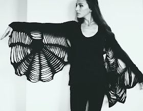 Woman showing off spider web wing long-sleeve black t-shirt that she created by cutting t-shirts. 