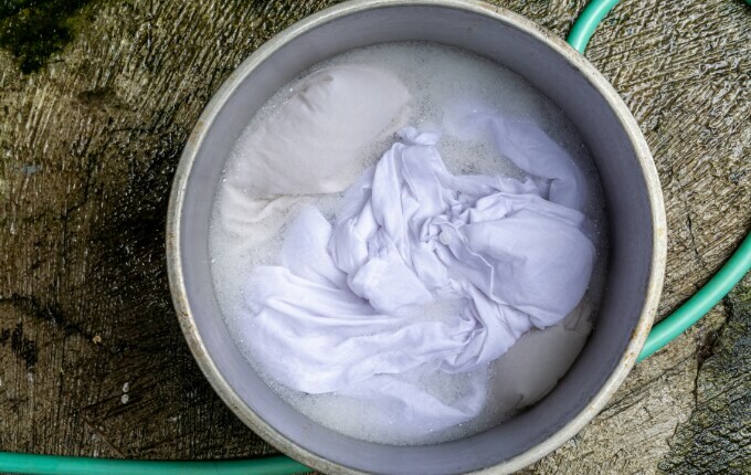 Shirts being soaked in soda ash in a bucket in preparation for tie dye craft