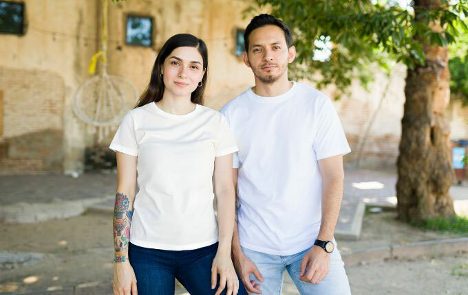 A man and a woman, both wearing white t-shirts, but the woman’s is discolored from color bleeding, and the man’s is crisp and bright white. 