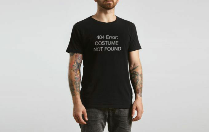 A tattooed man wearing a black short-sleeve t-shirt that reads: “404 Error: Costume Not Found”. 
