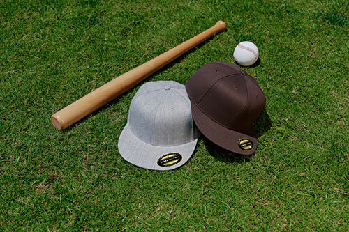 The Flexfit 6210 Adult Premium 210 Fitted® Cap, pictured in the colors "heather gray" and "black", alongside a wooden baseball bat. 