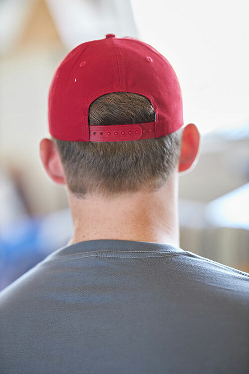 The back view of a person wearing the Big Accessories BX880SB Unstructured 6-Panel Snapback Cap in the color “red . 