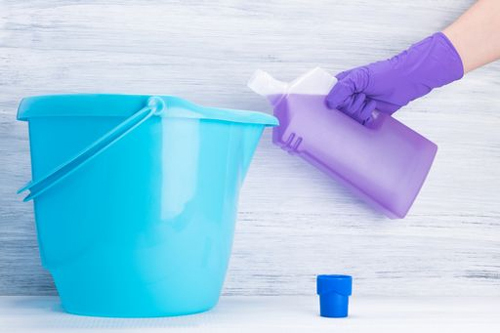 Blue bucket being filled with purple liquid