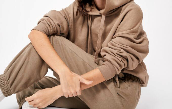 Woman wearing a dark tan colored matching jogger and hoodie sweatsuit.