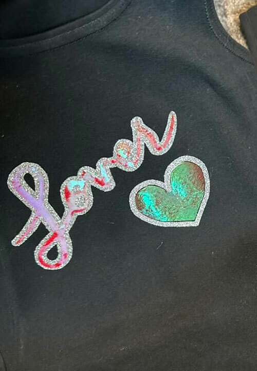  A black tank top with Taylor Swift’s “Lover” album’s logo made with holographic and glitter HTV.