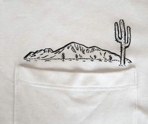 A white Bella+Canvas pocket tee with a desert scene printed above the pocket.