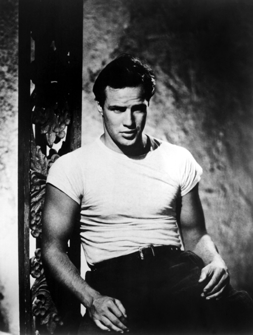 Black and white photo from 1951 of handsome movie star, Marlon Brando, wearing a white t-shirt in the movie titled, StreetCar Named Desire.