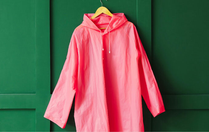 Coral windbreaker hanging against an emerald green wall. 