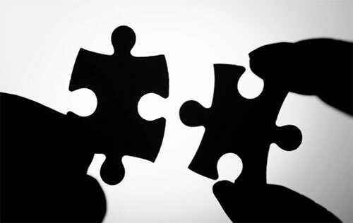 A silhouettes of two matching puzzle pieces about almost being placed together. 