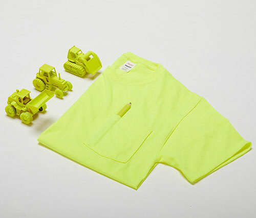 Hanes W110 in Safety Green tee with a highlighter pen in the pocket and three toy construction trucks of the same neon color are placed on the left.