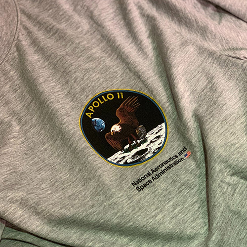 NASA and Apollo 11 breast print, featuring a bald eagle on the moon, placed on a gray heather t-shirt.
