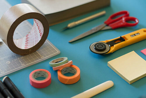 Tools needed to crop a t-shirt, including fabric scissors, a ruler guide and tape. 