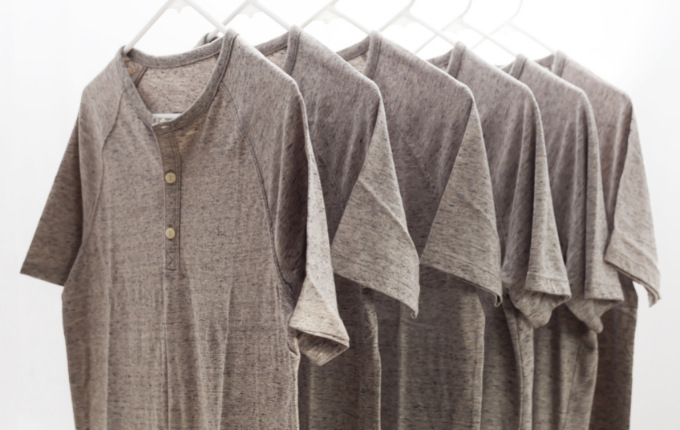 Light brown heathered henley shirts hanging up. 