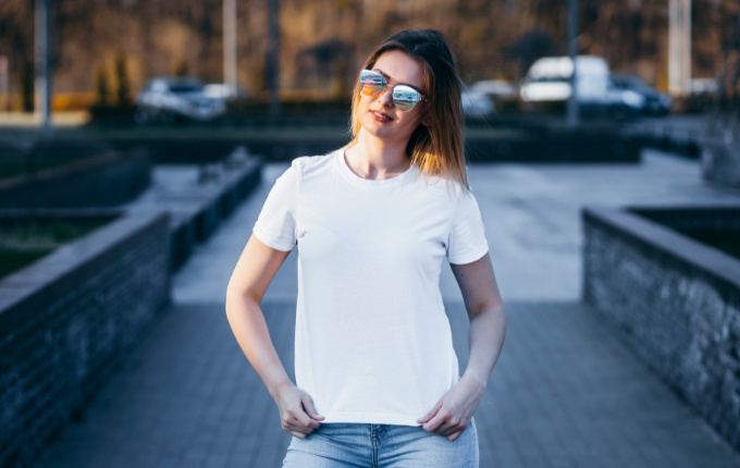 Woman outside in sunglasses and a white short sleeve crewneck t-shirt.