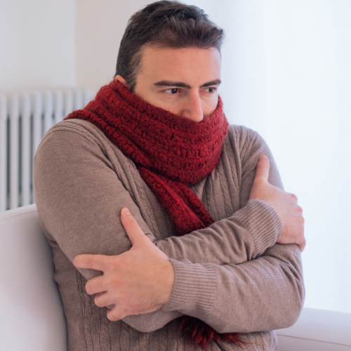 Cold man wearing tan sweater and red scarf wrapped around the bottom of his face.