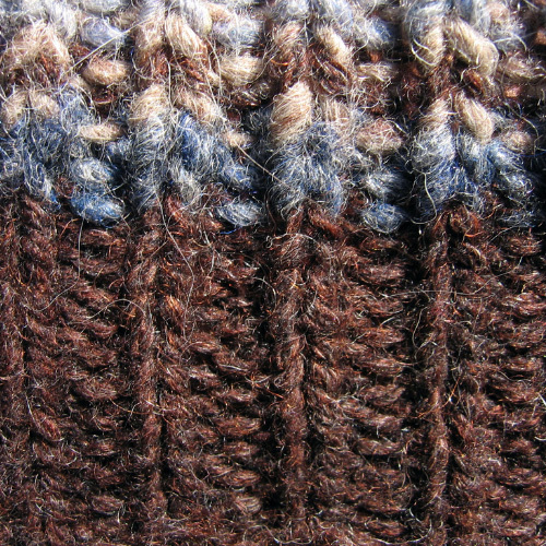 Close up of knitted wool yarn in browns and blue colors