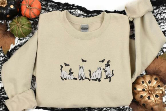 Sand-colored Gildan crewneck sweatshirt, embroidered with cats playing with bats, while dressed up in ghost costumes and witch hats. 