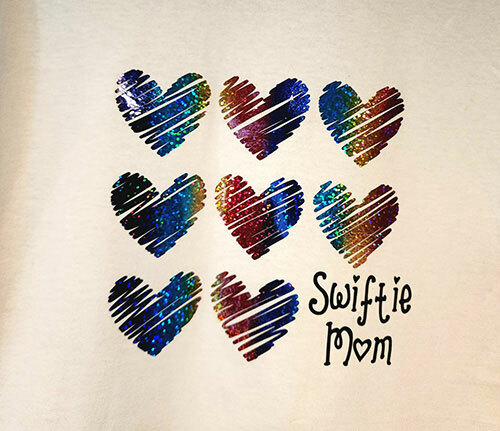 8 rainbow holographic HTV hearts and a “Swiftie Mom” printed on a white t-shirt from ShirtSpace by Shawn Gaglio.