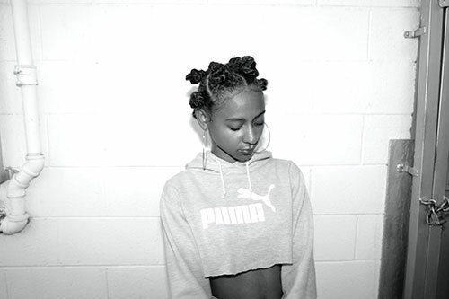 Woman wearing a cropped Puma hoodie with a raw edge on the bottom. 