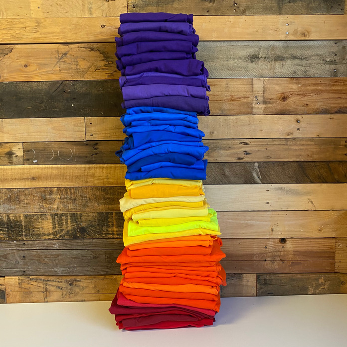 Stacked pile of folded Gildan G500 t-shirts in red, orange, yellow, blue and purple.