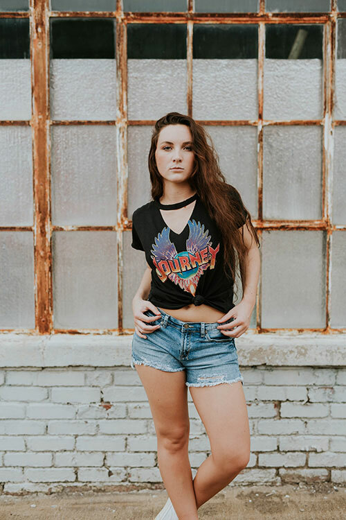 Young woman wearing cut-off jean shorts and custom cut-out Journey band t-shirt.