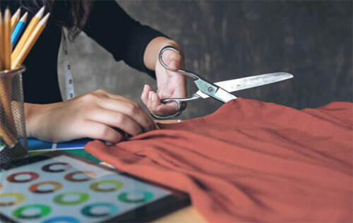 Person cutting fabric on their crafting table.