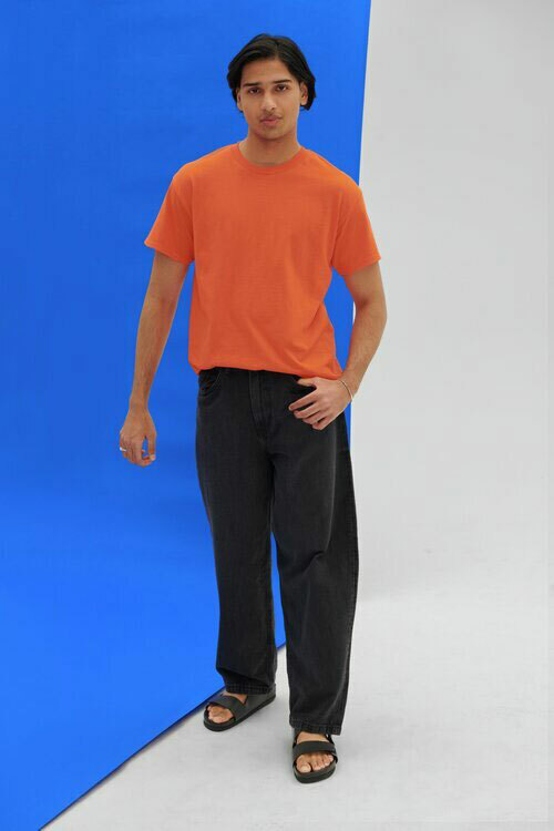 Man wearing an orange Gildan G800 t-shirt, paired with black jeans. 