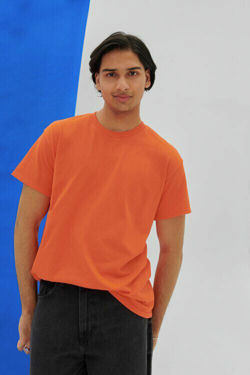 Man wearing an orange Gildan G800 t-shirt, paired with black jeans.